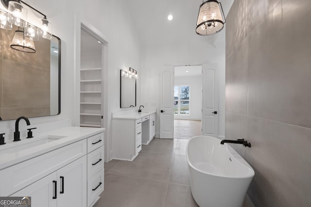 bathroom featuring a freestanding bath, two vanities, a sink, and tile walls