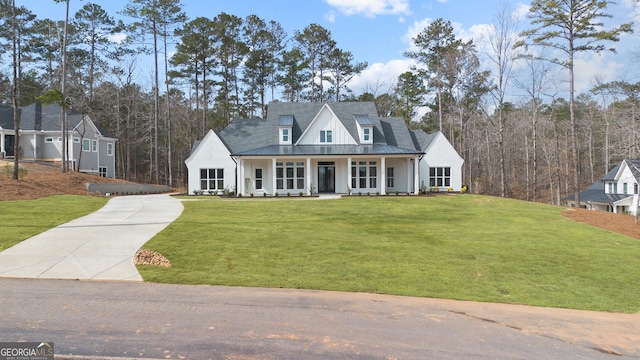 modern farmhouse with a porch, concrete driveway, and a front lawn