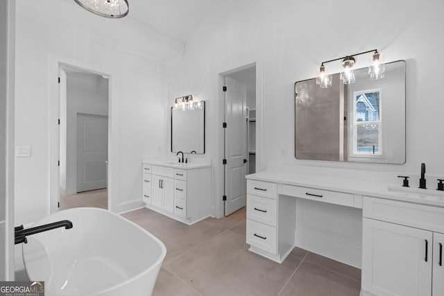 bathroom with a freestanding bath, two vanities, a sink, and tile patterned flooring