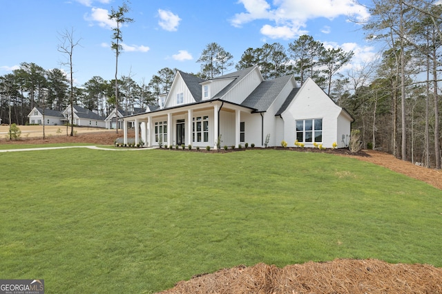 modern inspired farmhouse featuring board and batten siding, covered porch, a shingled roof, and a front lawn