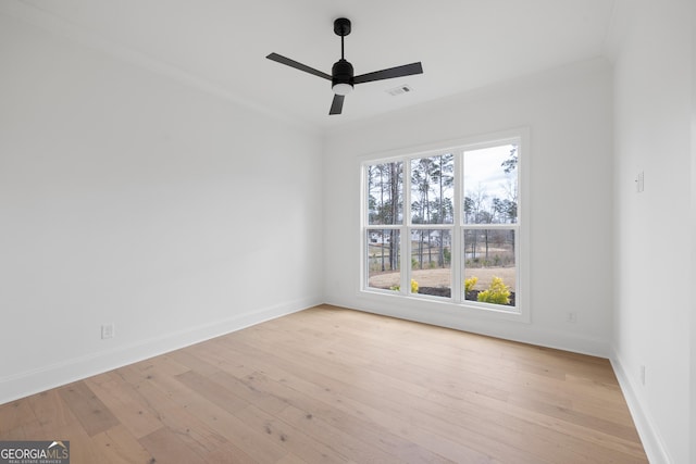 spare room featuring baseboards, light wood-style flooring, visible vents, and crown molding