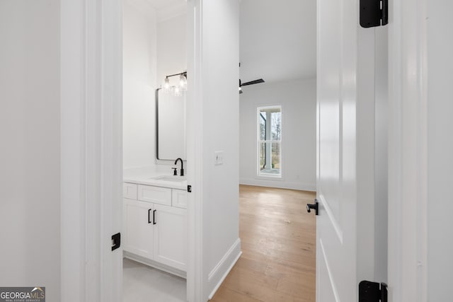 bathroom with baseboards, ornamental molding, wood finished floors, and vanity