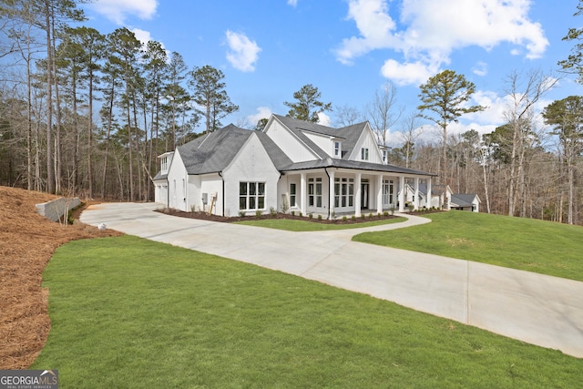 modern farmhouse featuring a porch, a shingled roof, a front yard, a standing seam roof, and driveway