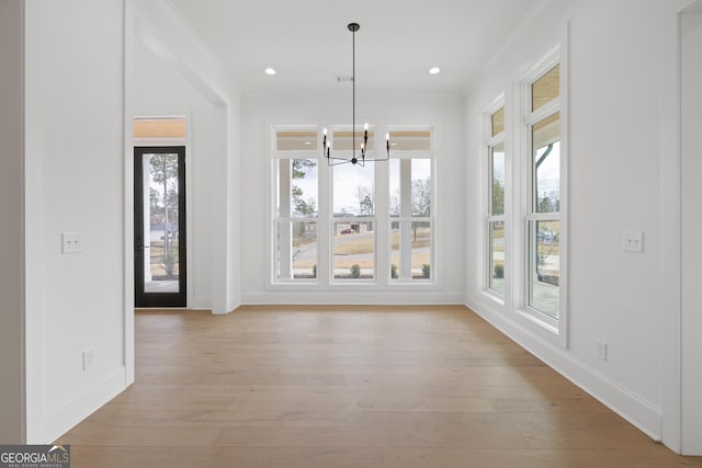 unfurnished dining area featuring light wood-style flooring, a chandelier, a wealth of natural light, and recessed lighting