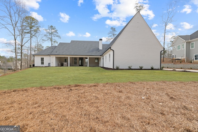 back of property featuring a lawn and a chimney