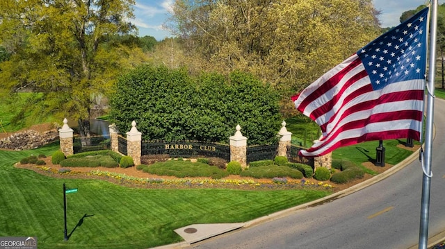 community / neighborhood sign featuring a lawn and fence