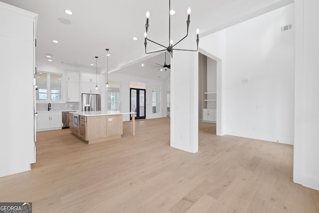 kitchen featuring stainless steel appliances, light wood-style floors, open floor plan, a kitchen island, and ceiling fan with notable chandelier