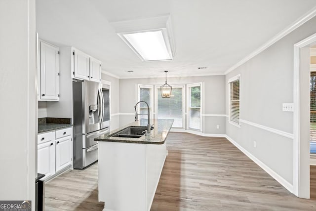 kitchen with white cabinetry, stainless steel fridge, sink, and light wood-type flooring