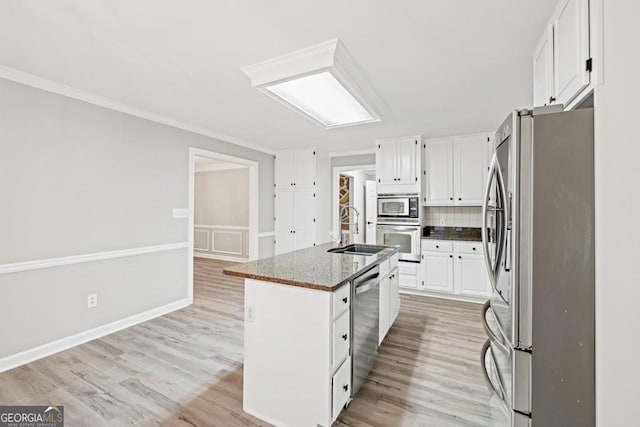 kitchen with white cabinets, appliances with stainless steel finishes, a kitchen island with sink, and sink