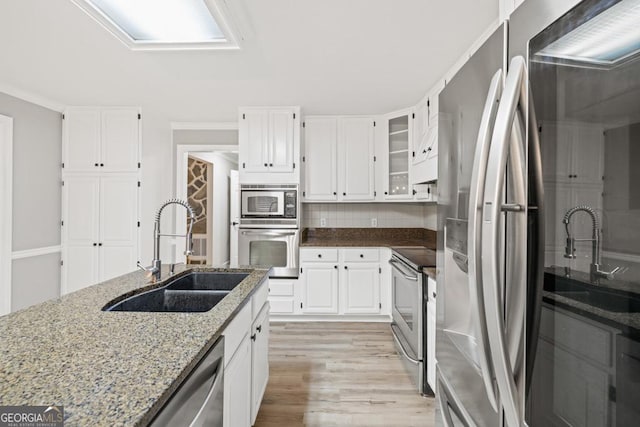 kitchen with white cabinets, appliances with stainless steel finishes, light hardwood / wood-style flooring, and sink