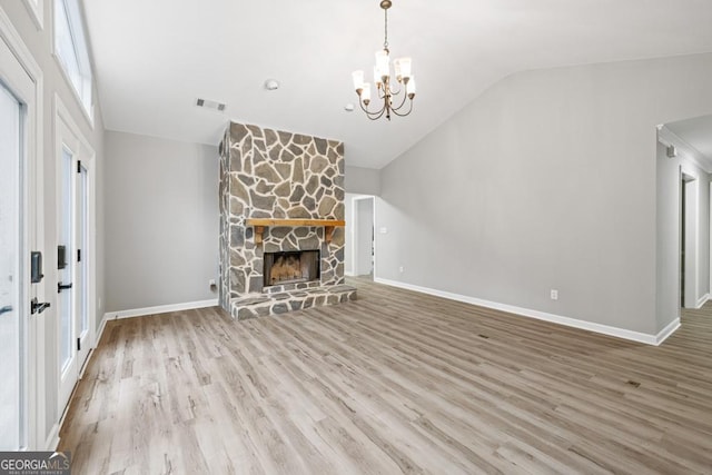 unfurnished living room featuring wood-type flooring, an inviting chandelier, a stone fireplace, and lofted ceiling