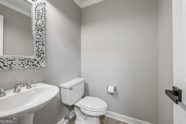 bathroom featuring wood-type flooring, toilet, crown molding, and sink