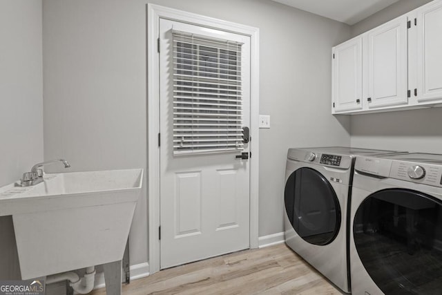 laundry area with washer and clothes dryer, light hardwood / wood-style flooring, cabinets, and sink