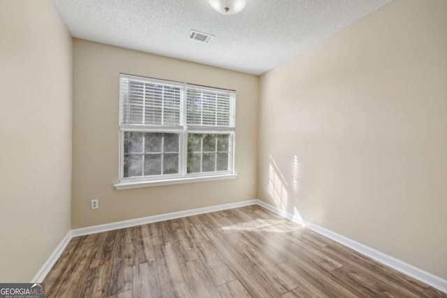 spare room featuring light hardwood / wood-style floors and a textured ceiling