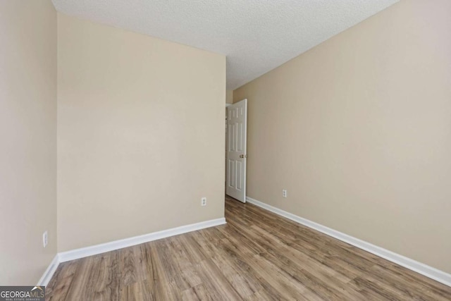 unfurnished room with a textured ceiling and hardwood / wood-style flooring