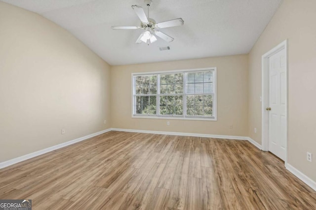 empty room with ceiling fan, lofted ceiling, and light hardwood / wood-style flooring