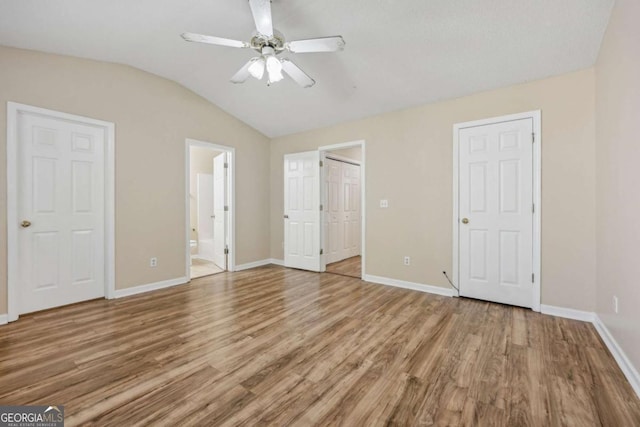 unfurnished bedroom featuring ensuite bath, ceiling fan, vaulted ceiling, and hardwood / wood-style flooring