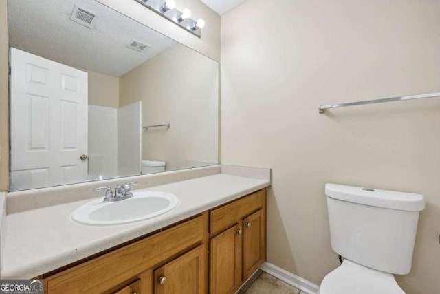 bathroom featuring a textured ceiling, vanity, and toilet