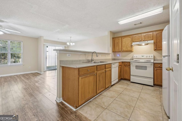 kitchen featuring white appliances, sink, light hardwood / wood-style flooring, a textured ceiling, and decorative light fixtures