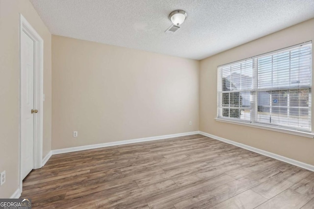 spare room with a textured ceiling and light wood-type flooring