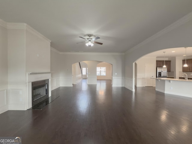 unfurnished living room with ceiling fan, dark hardwood / wood-style flooring, sink, and ornamental molding