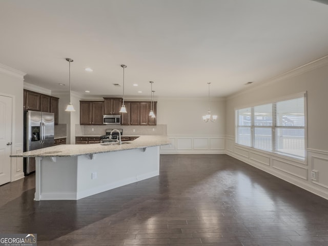 kitchen featuring pendant lighting, sink, stainless steel appliances, and a center island with sink