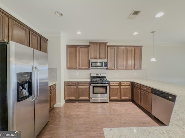 kitchen featuring kitchen peninsula, appliances with stainless steel finishes, ornamental molding, decorative light fixtures, and light hardwood / wood-style flooring