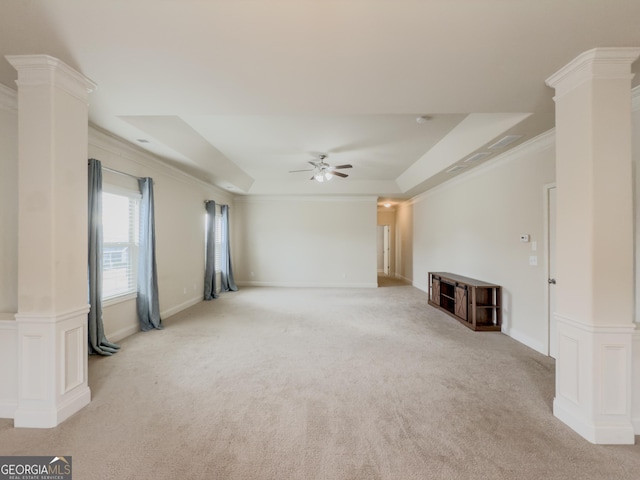 unfurnished living room with light colored carpet, ornate columns, a tray ceiling, and ornamental molding