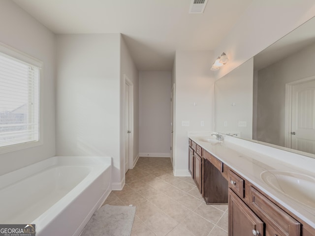 bathroom featuring a bathing tub, vanity, a healthy amount of sunlight, and tile patterned flooring