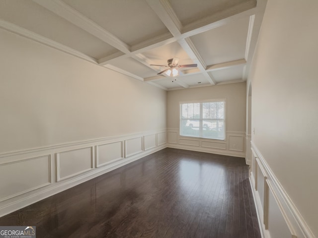 spare room featuring dark wood-type flooring, coffered ceiling, ceiling fan, ornamental molding, and beamed ceiling