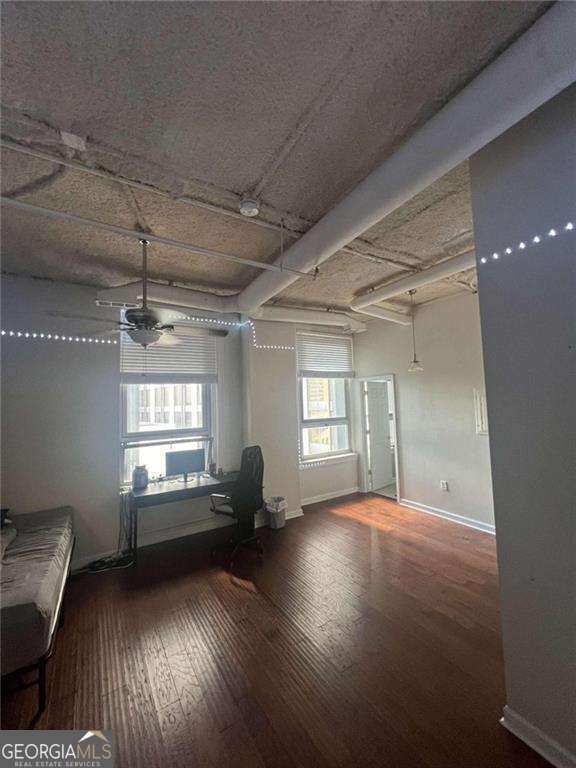 interior space with beam ceiling, a wealth of natural light, ceiling fan, and wood-type flooring