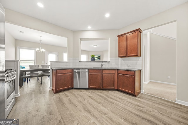 kitchen with stainless steel appliances, light wood-style floors, a sink, and decorative backsplash