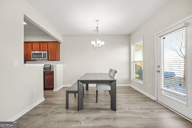 dining room with baseboards, light wood finished floors, and a notable chandelier