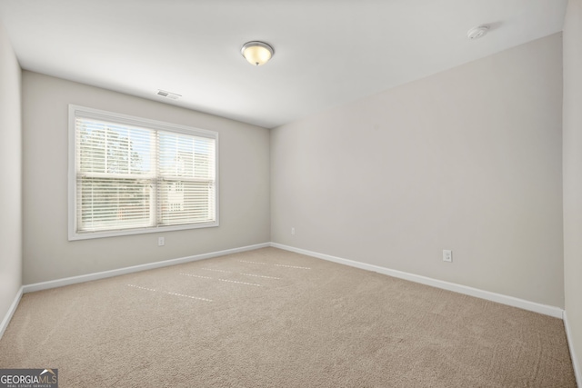 carpeted spare room featuring visible vents and baseboards