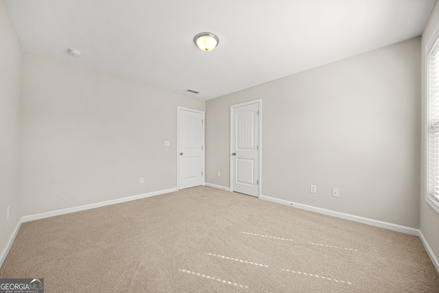 spare room featuring a healthy amount of sunlight, carpet, visible vents, and baseboards