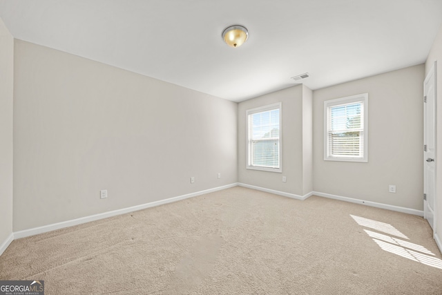 spare room featuring light carpet, baseboards, and visible vents