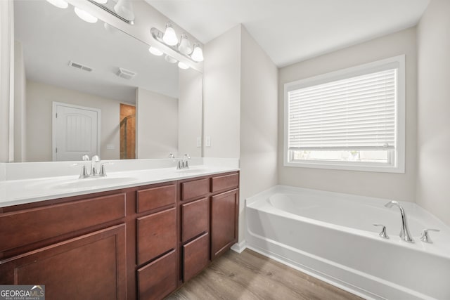 full bathroom with double vanity, visible vents, a sink, and a bath