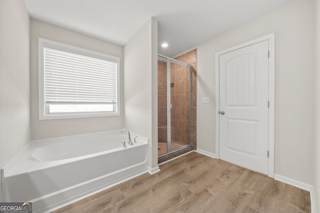 bathroom featuring a garden tub, a stall shower, wood finished floors, and baseboards