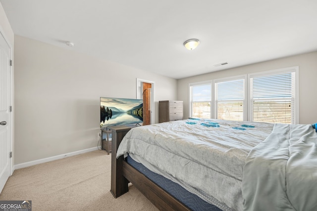 bedroom with light carpet, a spacious closet, visible vents, and baseboards