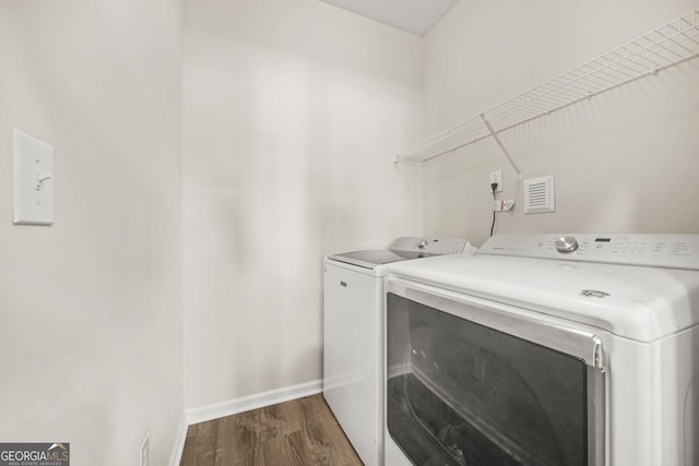 clothes washing area featuring dark wood-type flooring, washer and dryer, laundry area, and baseboards