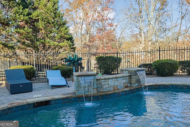 view of swimming pool with pool water feature and a patio area