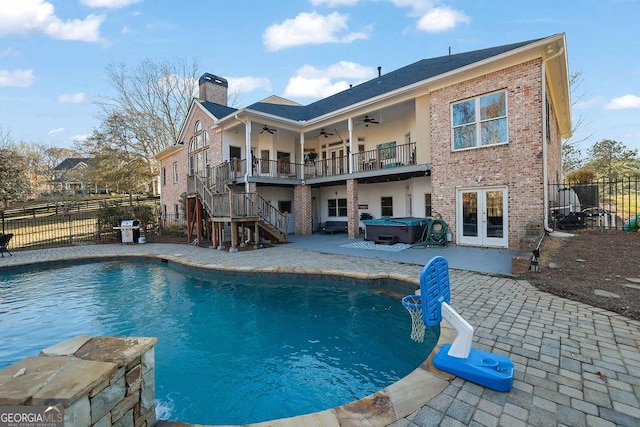 back of house with ceiling fan, a swimming pool with hot tub, a patio area, and french doors