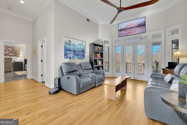 living room featuring a high ceiling, ceiling fan, and crown molding