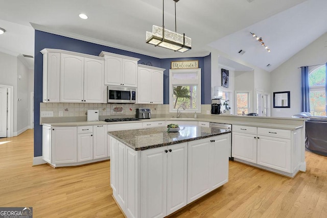 kitchen featuring kitchen peninsula, appliances with stainless steel finishes, a center island, and backsplash