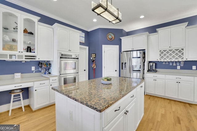 kitchen with white cabinetry, stainless steel appliances, decorative light fixtures, and light wood-type flooring