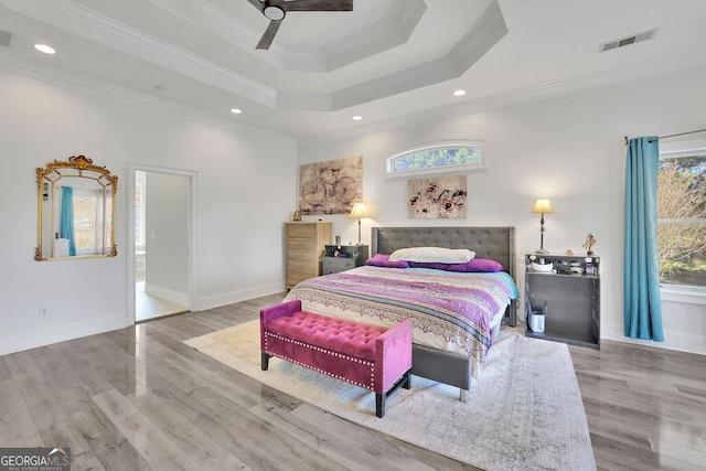 bedroom with a tray ceiling, ceiling fan, light hardwood / wood-style flooring, and ornamental molding