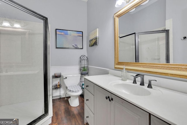 bathroom featuring vanity, toilet, wood-type flooring, and a shower with shower door