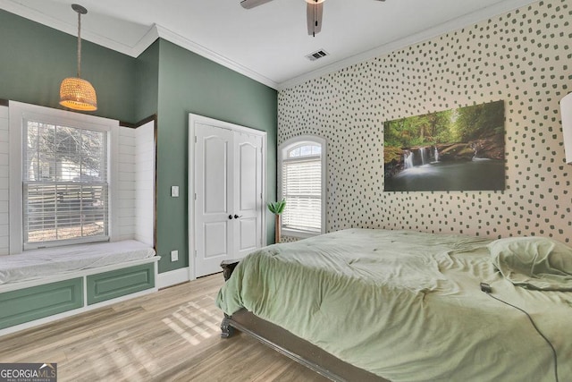 bedroom with ceiling fan, a closet, light wood-type flooring, and ornamental molding