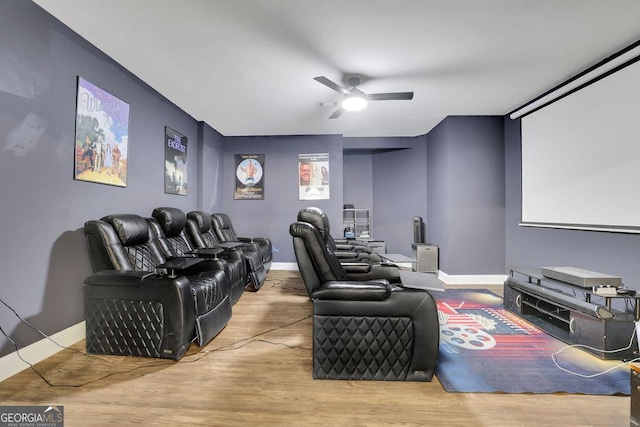 cinema room with light hardwood / wood-style flooring and ceiling fan