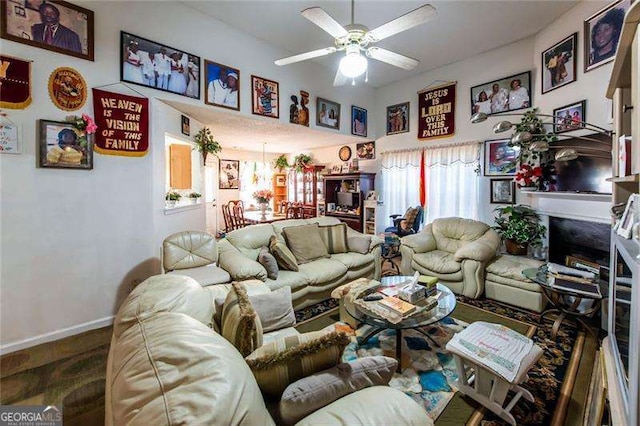 living room featuring hardwood / wood-style floors, ceiling fan with notable chandelier, and a fireplace